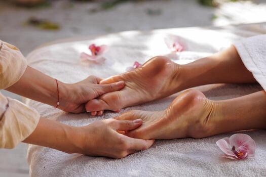 Home foot massage therapy outdoors at spa with therapist and orchids photo